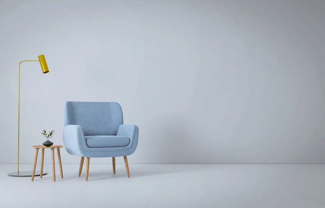 A blue armchair, wooden side table, and brass floor lamp